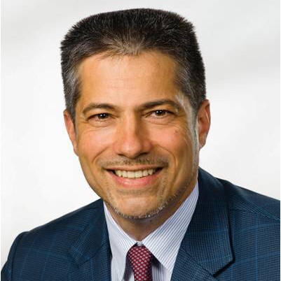 A man in a suit and tie smiling for the camera.
